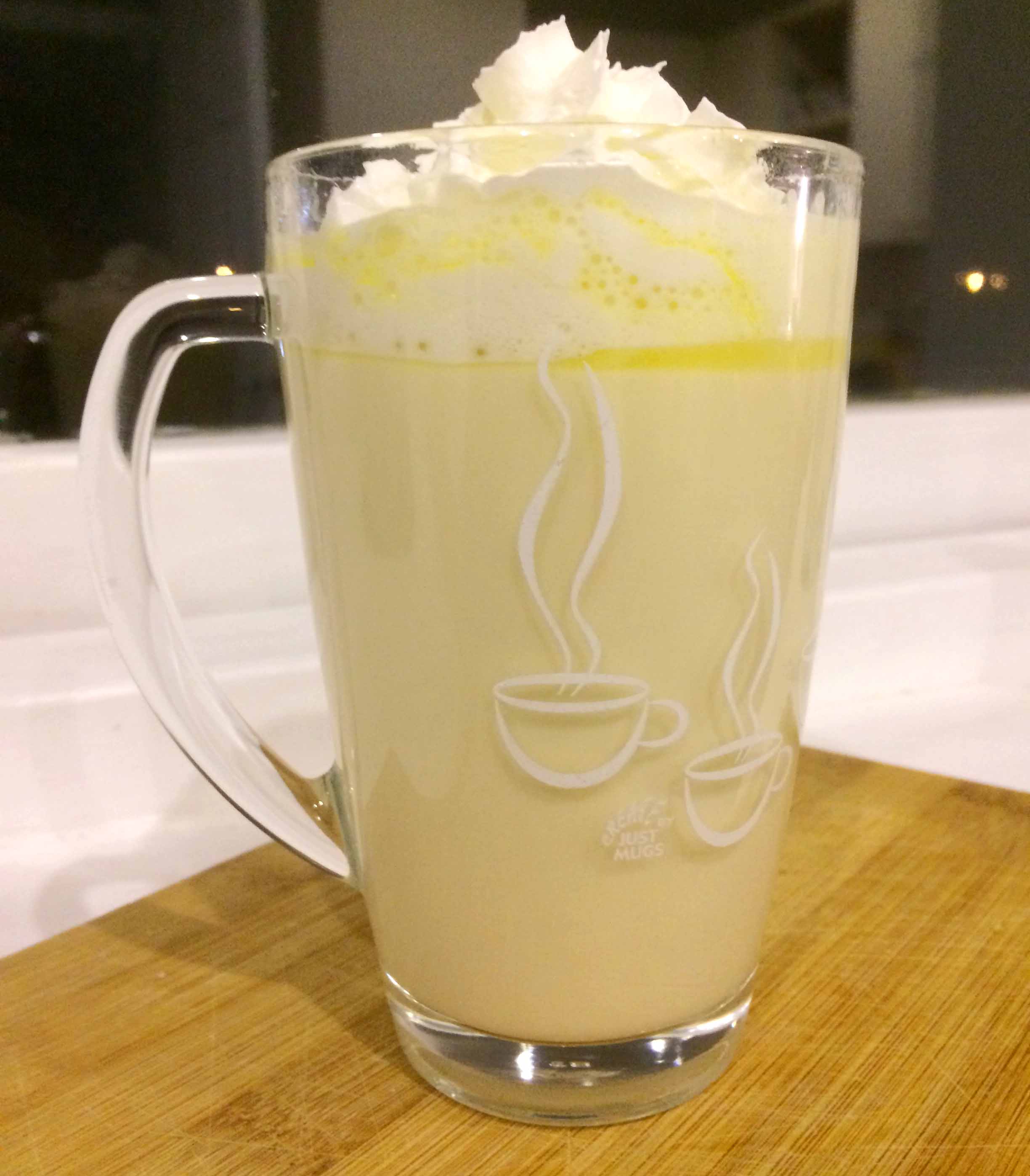 Valencia Orange White Hot Chocolate served with whipped cream, served in a clear glass mug.