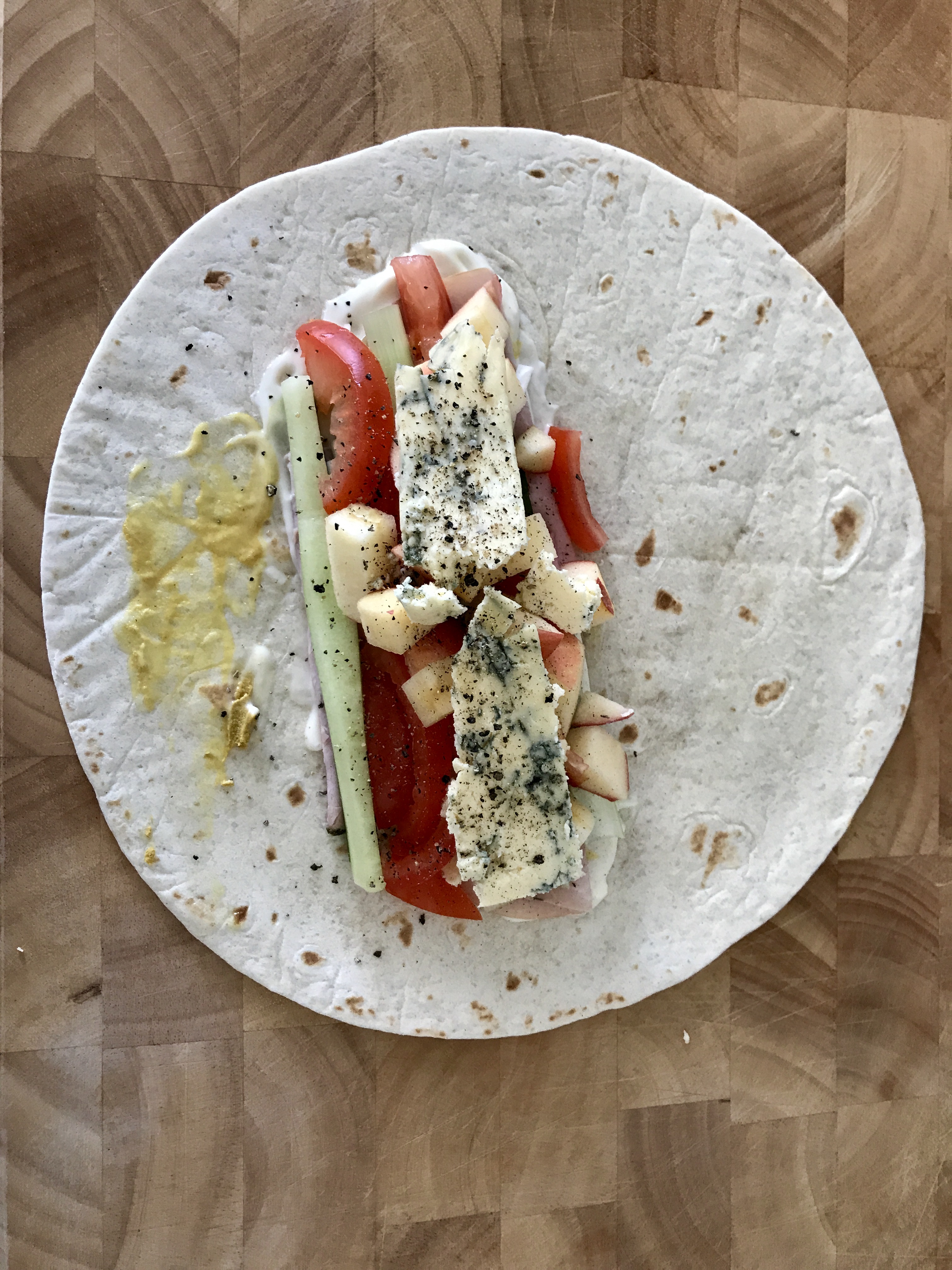 Pork, Apple, Blue Cheese Wrap open on a chopping board, viewed from above.